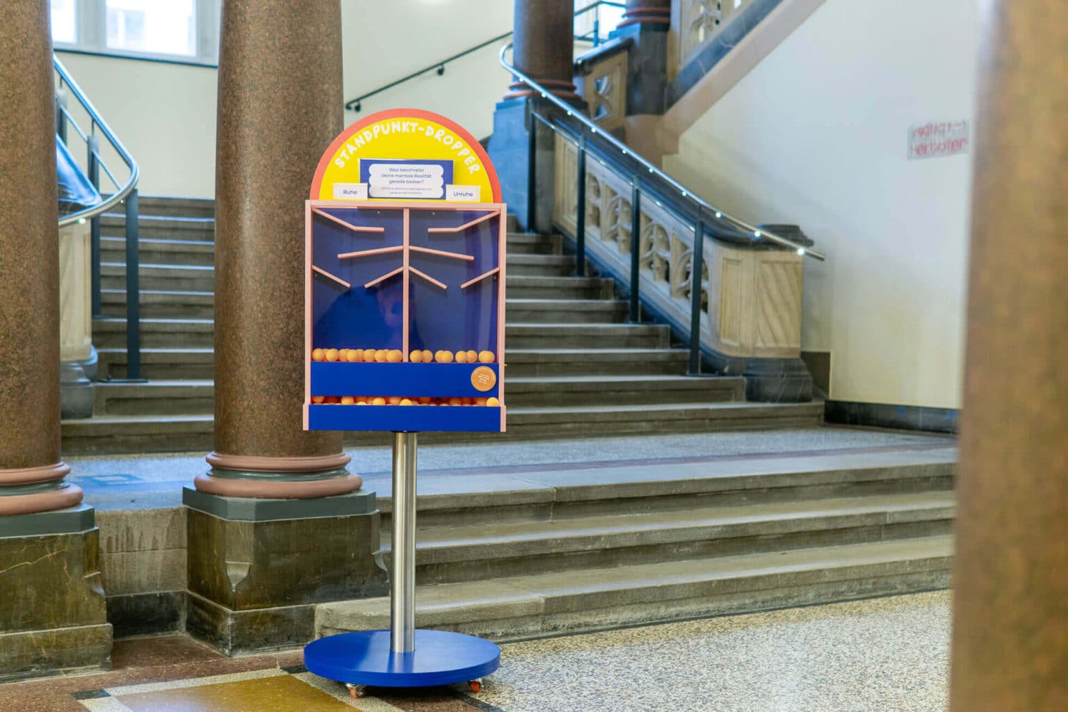 Standpunkt Dropper steht in einem Foyer mit Säule vor einer Treppe